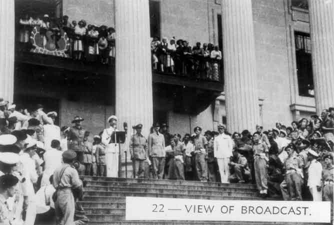 022 - View of broadcast
Admiral Mountbatten giving a public address on the steps of the Singapore Municipal Buildings during the Japanese surrender ceremony. To the left of Mountbatten is Lieutenant General Slim and to the right are Lieut. General Wheeler and Air Chief Marshal Sir Keith Park. 
