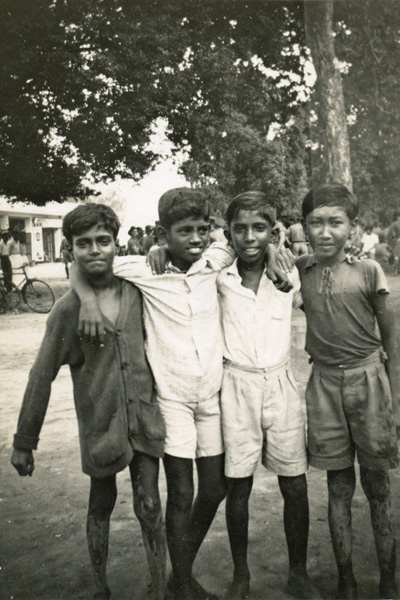 Malayan village
Malayan village.  Annotated on reverse:

"This snap taken by a pal of mine in the street of a nearby village gives some idea of the "local talent" Usually the natives are very reluctant about being photographed, but these young hopefuls have no scruples. The kids of all races get on well with the Aussies"

Left to right:
1) ?
2) ?
3) ?
4) ?

Keywords: 20120722 NX30114