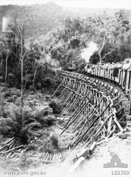 Trestle bridge near Hintok, Thailand
Hintok, Thailand. 19 October 1945. The curved trestle bridge approximately 154 kilometres north of Nong Pladuk (also known as Non Pladuk), or 260 kilometres south of Thanbyuzayat. This bridge, approximately one kilometre south of Hintok Station, was one of six trestle bridges between Konyu (Hellfire Pass) 152 kilometres north of Nong Pladuk, and Hintok 155 kilometres north of Nong Pladuk. This bridge has been confused with the Pack of Cards bridge which was sited just north of Hintok Station. It was a three tiered trestle bridge approximately 400 yards long and eighty feet high. During its construction it fell down three times, hence its name Pack of Cards. This site was abandoned in September 1943, when a high earth and rock embankment adjacent to it was completed. By the end of the war in August 1945, the bridge structure had completely collapsed and disappeared under jungle regrowth. There is no known photograph of the Pack of Cards bridge.
