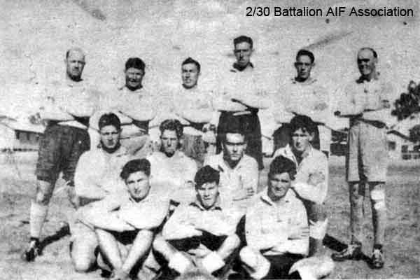 A Company Football Team
This photo appeared in Makan 172 and Makan 336.

"Do you remember these boys? It's an old photograph taken at Bathurst. It's the "A" Co. Football Team. They were never beaten in any match!"

Left to right:

Back row (standing):
1) NX70486 - BOOTH, Edward Holroyd (Baldy or Ward), Capt. - D Coy. O/C D Coy. Pl. C.M.G.
2) NX34443 - EVANS, Garrett William (Garry or Porky), L/Cpl. - A Company, 8 Platoon
3) NX51454 - ABRAHAMS, Harry Stirling (Harry), Cpl. - A Company, 7 Platoon
4) NX54846 - ARNEIL, Stanley Foch (Horse or Stan), Sgt. - A Company, 7 and 8 Platoon
5) NX56869 - BLANSHARD, Douglas Copeland (Doug), Sgt. - A Company, 8 Platoon
4) NX47953 - WILLIAMS, Frank Edward (Ned), Pte. - A Company, 8 Platoon

Middle row (kneeling):
1) NX47952 - VEIVERS, Charles Thomas (Joe), Pte. - A Company, 9 Platoon
2) NX33290 - CHAPMAN, Keith Milford (Chappie), Pte. - A Company, 8 Platoon
3) NX4416 - SWAIN (Swanson), Victor Leonard, Pte. - A Company
4) NX25458 - WATT, Edward Louvain (Ted), Cpl. - A Company, 9A Platoon

Front row (sitting):
1) NX4417 - PEARCE (Pearson), Bruce Donald (Donald Bruce) (Joe), Pte. - A Company, 8 Platoon
2) NX54534 - ASGILL, Colin Cyril (Matey), Pte. - A Company, 8 Platoon
3) NX47564 - DOWLING, Kevin John, Pte. - A Company, 9 Platoon (as listed in Makan 172)
or ? - SWAIN, K.T. (as listed in Makan 336)
Keywords: Makan172 Makan336 ACompanyFootballTeam