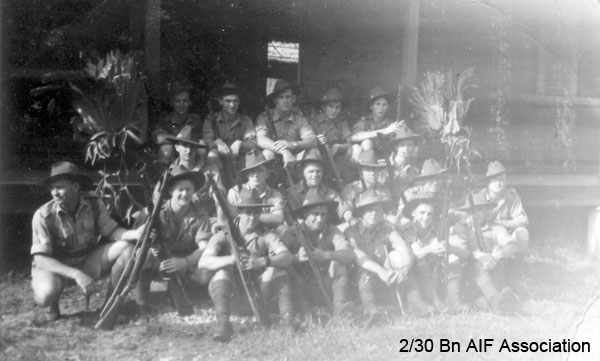 Mortar Platoon at Batu Pahat
"Snap of the boys outside our hut in the new camp. Note staghorns - there are hundreds of them around here. Don"

Front row, seated on ground, left to right:
1. Unknown
2. Unknown
3. Unknown
4. Unknown
5. Unknown

Second row, squatting, left to right:
1. Unknown
2. NX32306 - MACIVER, Donald Gunn (Bluey), Cpl. - HQ Company, Mortar Platoon
3. Unknown
4. Unknown
5. Unknown
6. Unknown
7. Unknown

Third row, seated on steps of hut, left to right:
1. Unknown
2. Unknown

Fourth row, seated on verandah of hut, left to right:
1. Unknown
2. Unknown
3. Unknown
4. Unknown
5. Unknown
Keywords: batupahat